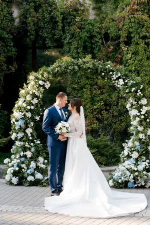 Happy couple celebrating wedding with flower bouquet outdoors.