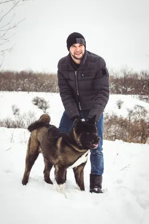 Happy man skiing with dog in snowy forest landscape.