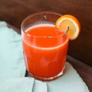Fresh orange tea in glass with ice cubes.