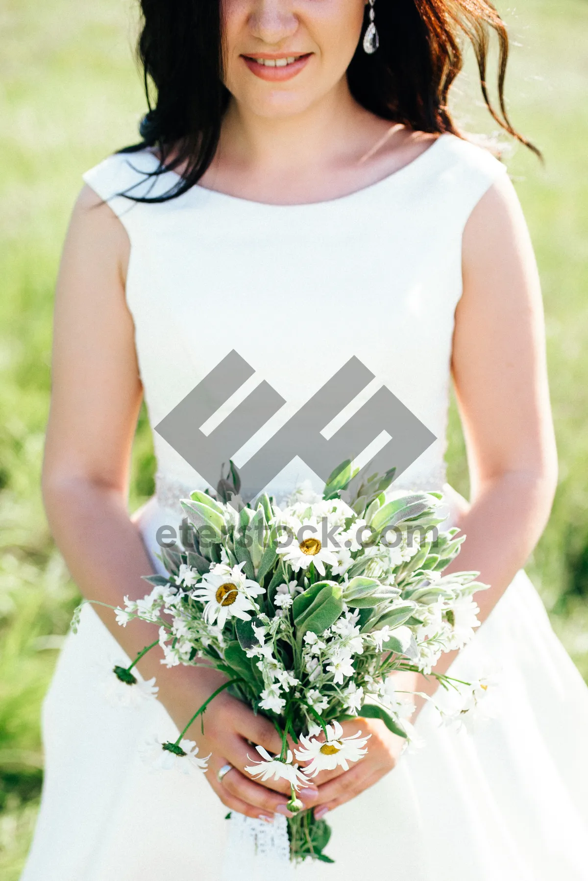 Picture of Attractive bride smiling outdoors with flower bouquet