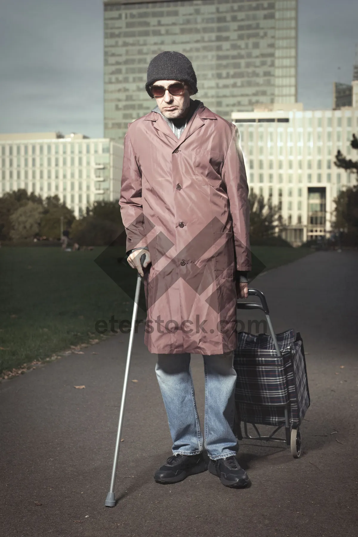 Picture of Happy man in trench coat with crutch smiling.