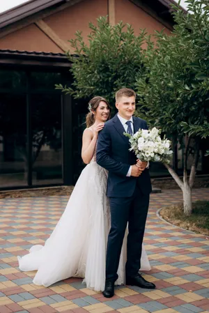 Happy married couple celebrating wedding outdoors with flowers