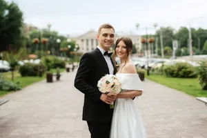 Happy groom and bride with bouquet outdoors