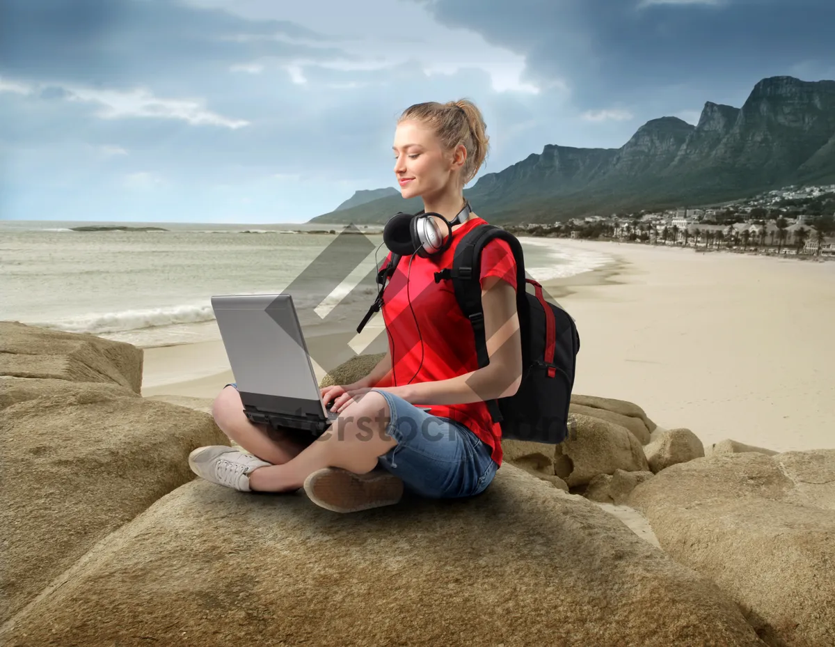 Picture of Happy businessman working on laptop at the beach.