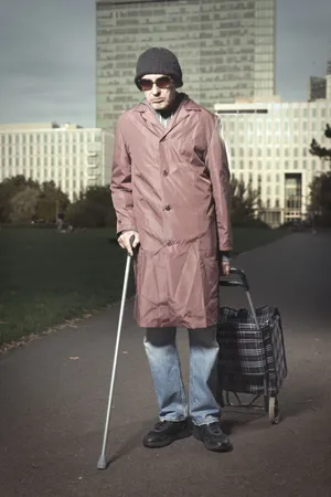 Happy man in trench coat with crutch smiling.