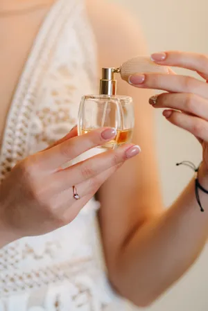 Hand holding glass perfume bottle with lotion close-up.