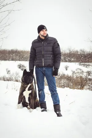 Happy man skiing with his giant schnauzer in snowy landscape