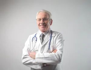 Smiling male doctor in professional medical attire.