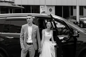 Happy couple in wedding limousine smiling and sitting.