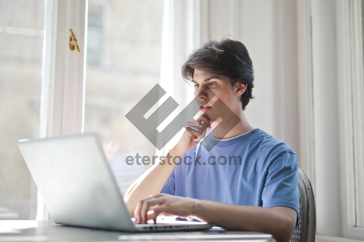 Picture of Happy businessman working on laptop at home office