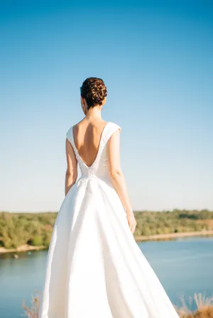 Attractive brunette bride smiles in elegant wedding dress.