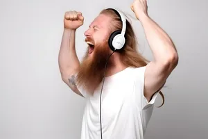 A Caucasian man energetically dancing with headphones on, his body moving to the rhythm, radiating happiness and positivity, isolated on perfect white background.