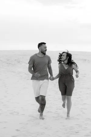 Happy couple walks along sandy beach at sunset