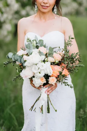 Happy bride holding bouquet of roses in garden wedding.