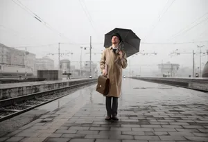 Man with umbrella walking on rainy city street