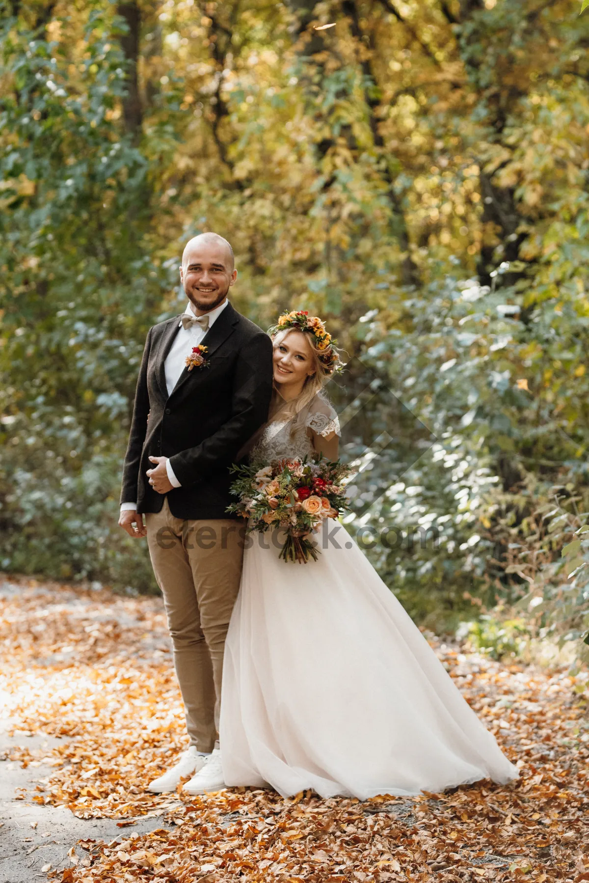 Picture of Happy groom smiling with bride on wedding day outdoors.