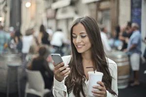 Happy brunette businesswoman sitting at cafe holding coffee