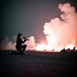 Silhouette of Man with Flamethrower at Sunset Beach