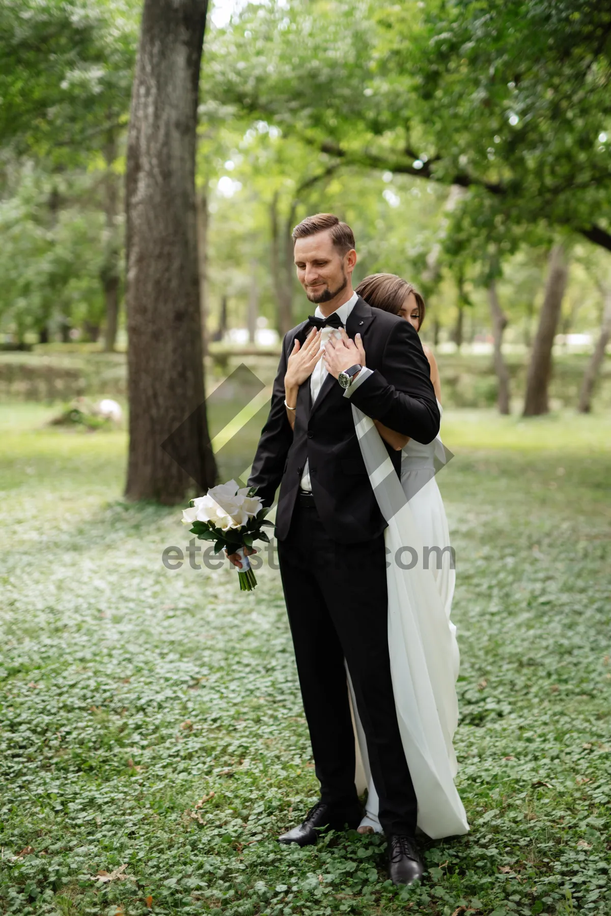 Picture of Happy newlywed couple in park with bouquet