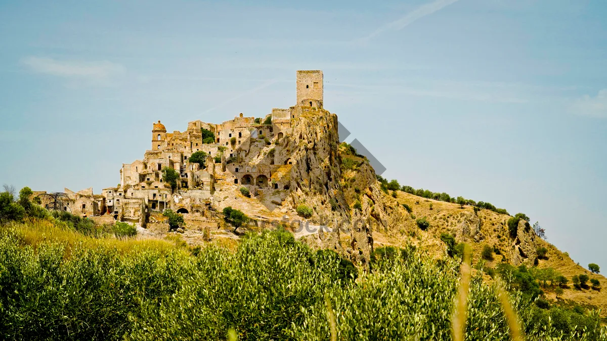 Picture of Ancient castle atop scenic mountain under cloudy sky.