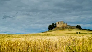 Medieval castle in rural countryside under summer sky.