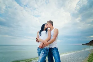 Happy Couple on Beach with Binoculars Watching Sunset