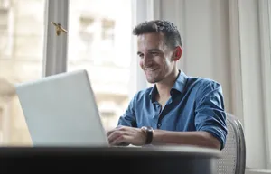 Happy male executive working on laptop in office