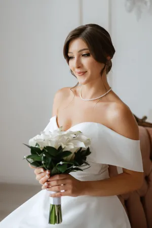 Attractive bride in elegant gown with flower bouquet