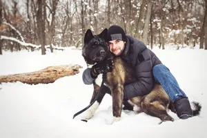 Man skiing with happy dog in snowy forest landscape