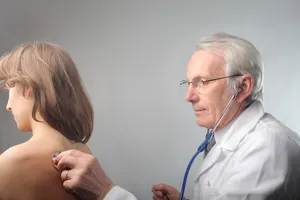 Elderly male doctor with stethoscope in clinic.