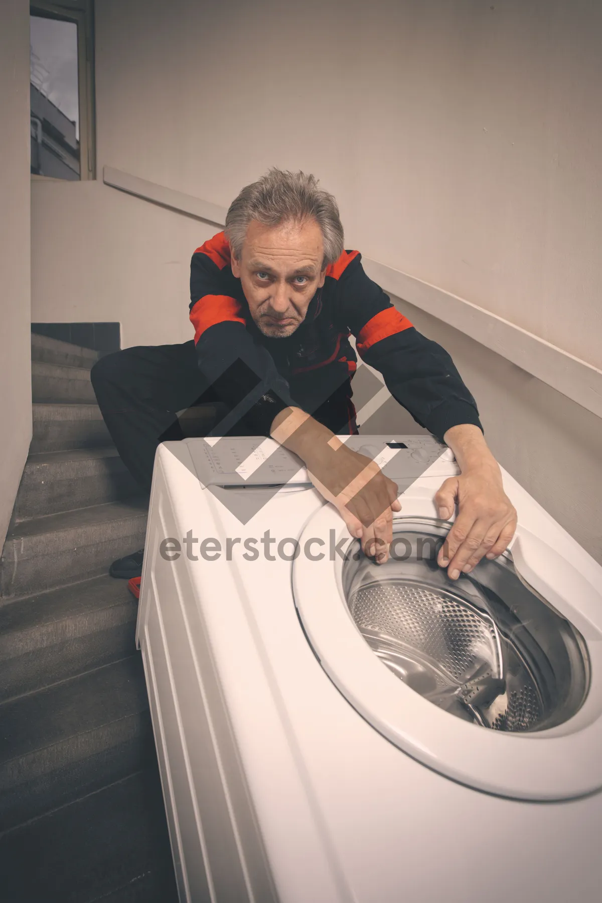 Picture of Man doing laundry at home with white washer appliance