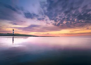 Orange sunset over tranquil ocean waves on beach shore.
