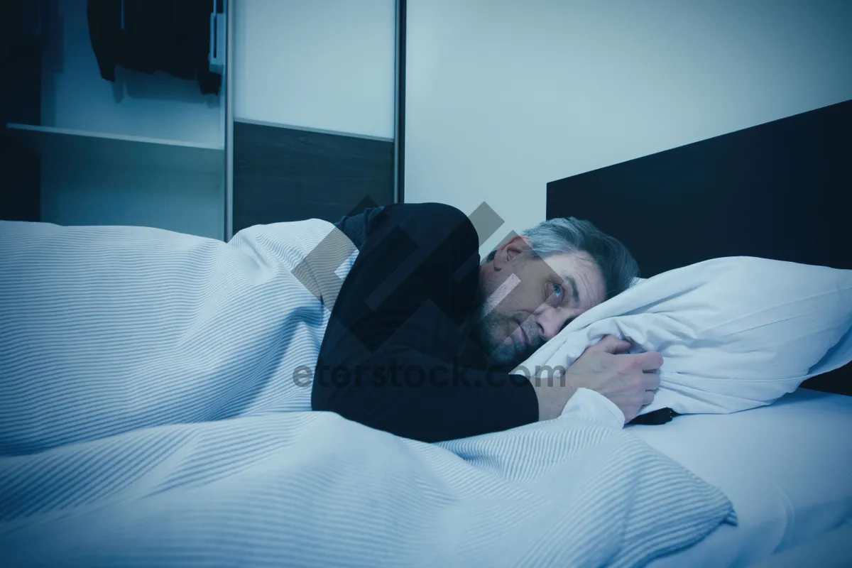 Picture of Man relaxing on a cozy sofa in bedroom.