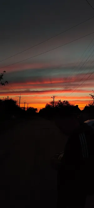 Orange sunset sky with silhouette cloud and cable wire.