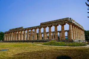 Roman viaduct over ancient city ruins under blue sky.