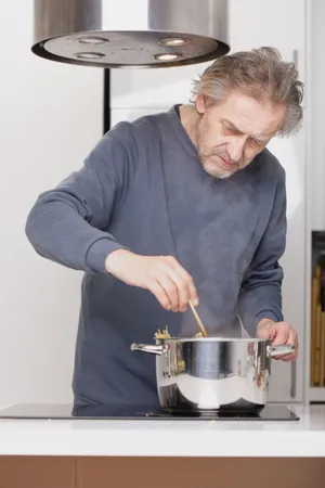 Man cooking in kitchen with steel drum container.