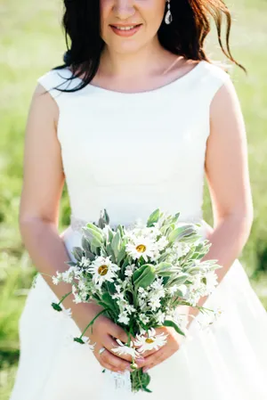 Attractive bride smiling outdoors with flower bouquet