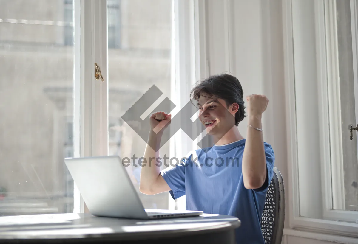 Picture of Happy male businessman working on laptop in office