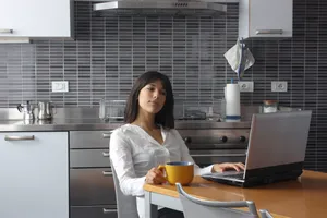Happy businesswoman smiling at laptop in restaurant office.