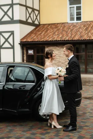 Happy newlywed couple smiling on wedding day with flower bouquet