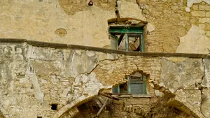 Historic stone building with balcony and ancient wall doorway