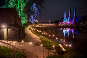 City skyline with suspension bridge over river at dusk