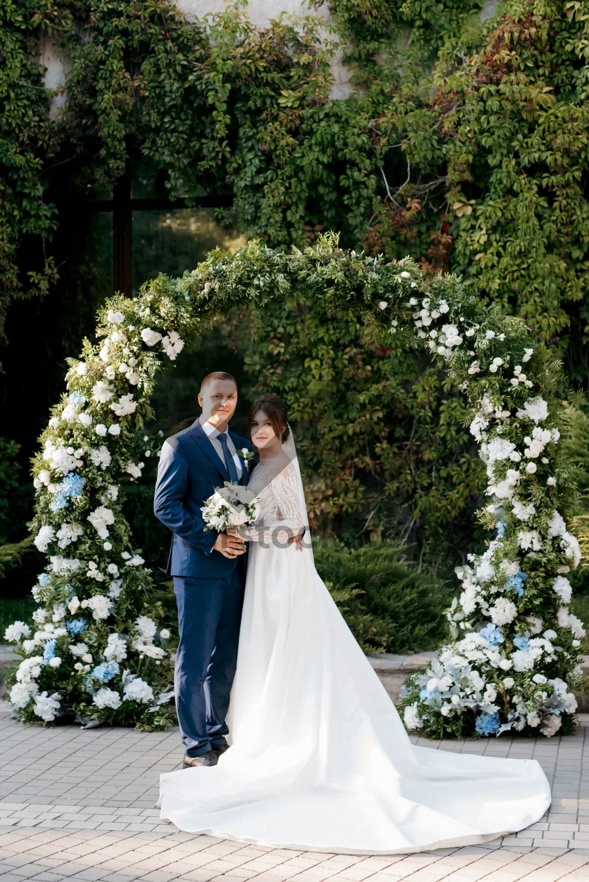 Picture of Happy wedding couple smiling outdoors with flowers.