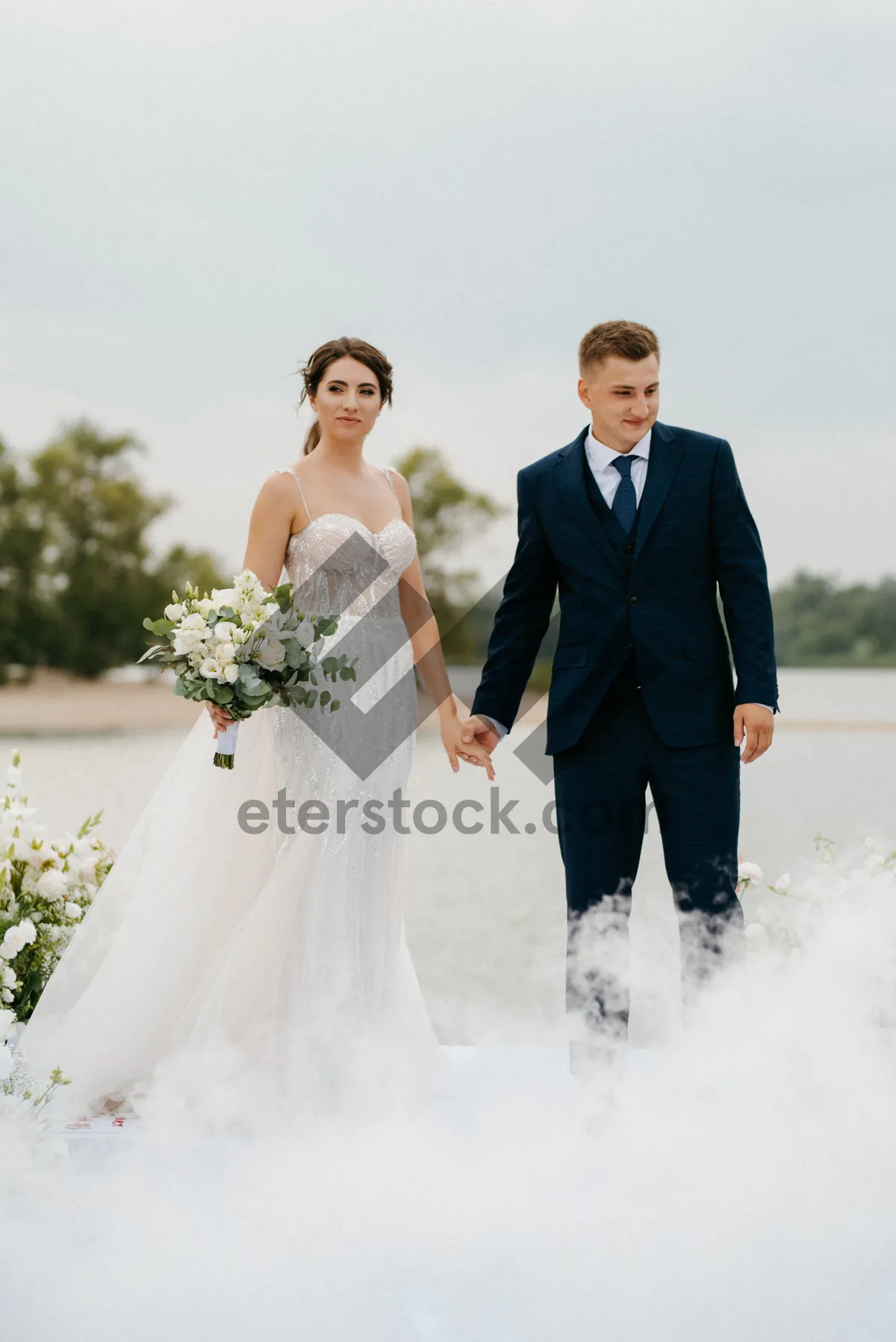 Picture of Happy newlywed couple outdoors on wedding day smiling together
