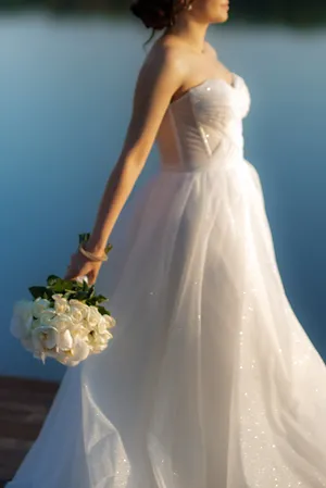 Happy newlywed couple in wedding attire holding flowers