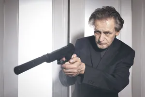 Professional businessman holding microphone and gun in suit portrait.