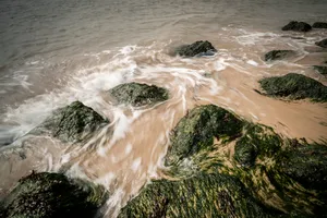 Tropical beach with waves crashing on rocks
