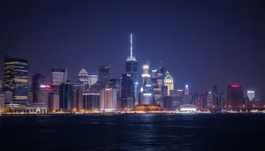 Modern skyline with city lights reflecting on river at sunset.