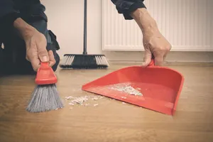 Person cleaning ottoman with broom and pad