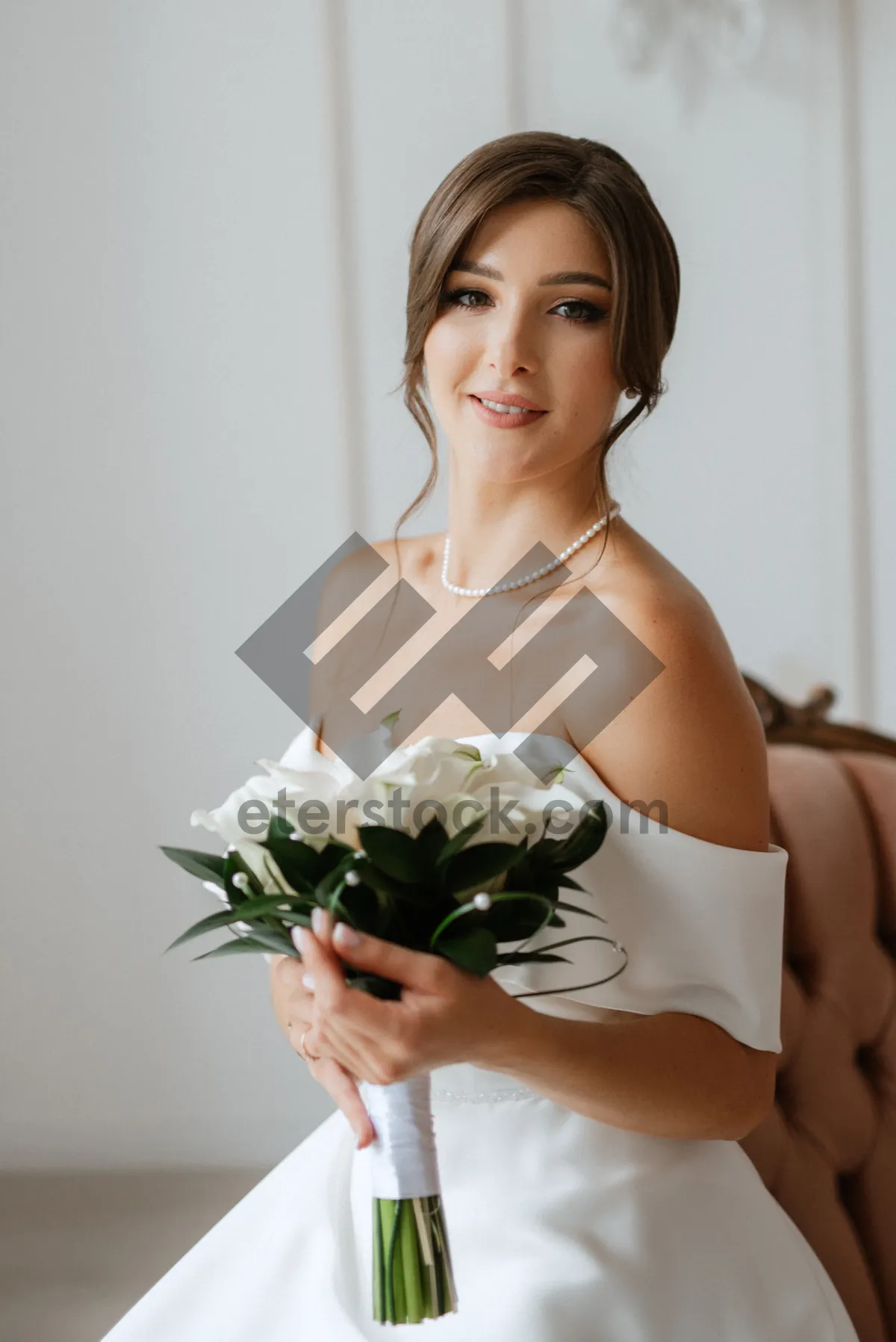 Picture of Attractive brunette bride with bouquet smiling happily in wedding dress